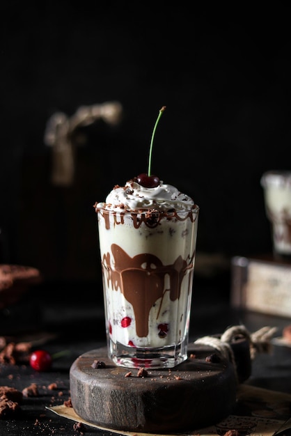 A glass of chocolate milkshake with a chocolate cherry on top