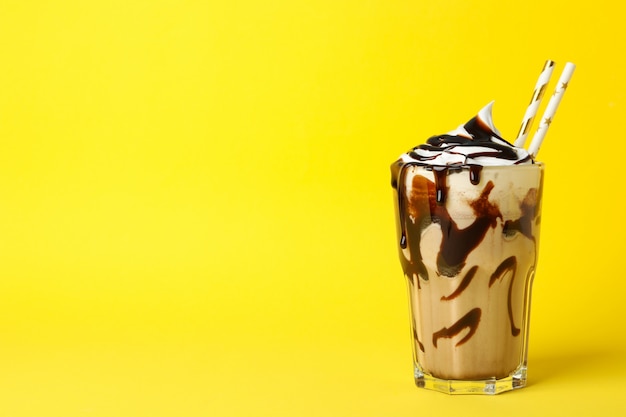 Glass of chocolate milkshake on yellow