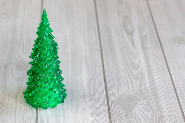 Glass Christmas tree closeup on a light wooden background with an empty space