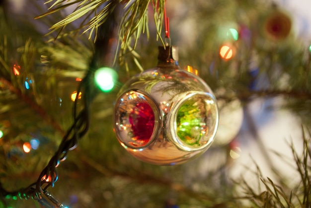 Photo glass christmas tree decoration on a background of a christmas tree with lights