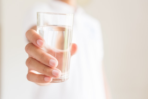 Un bicchiere di acqua minerale pulita nelle mani dell'uomo. concetto di bevanda salutare