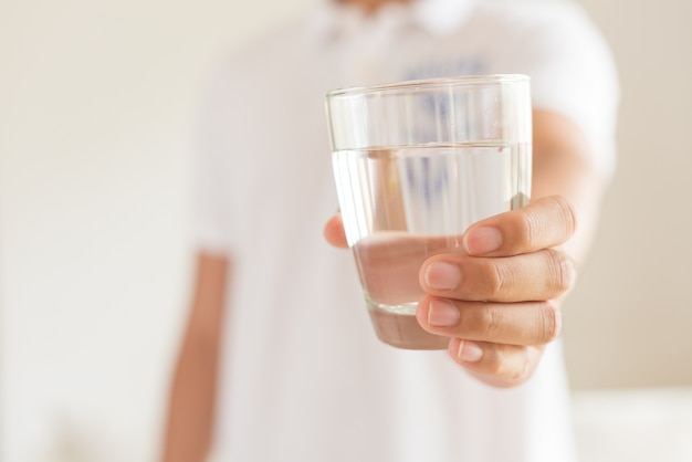 Un bicchiere di acqua minerale pulita nelle mani dell'uomo. bevanda sana di concetto.