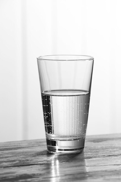 Glass of clean mineral water on old color wooden surface and planks background