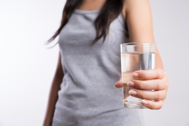 A glass of clean mineral water in woman's hands. Concept of healthy drink