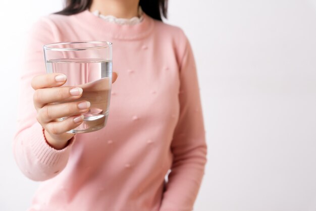 A glass of clean mineral water in woman's hands. Concept of healthy drink