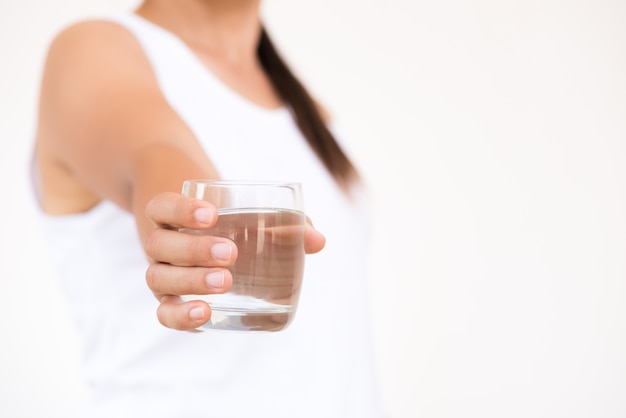 A glass of clean mineral water in woman's hands.