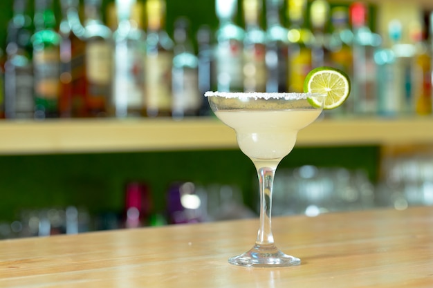 Glass of cocktail decorated with fruits at bar counter.