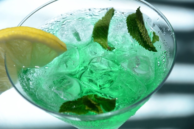 Bicchiere di fata verde da cocktail con limone e foglie di menta liquore alla menta dolce rinfrescante con ghiaccio e rum di assenzio cubetti di ghiaccio e vodka