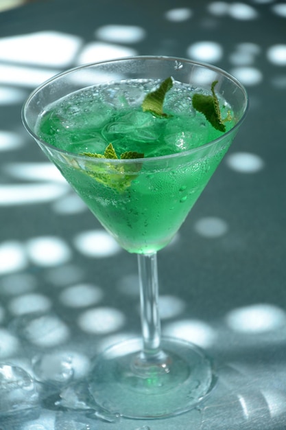 Bicchiere di fata verde da cocktail con limone e foglie di menta liquore alla menta dolce rinfrescante con ghiaccio e rum di assenzio cubetti di ghiaccio e vodka