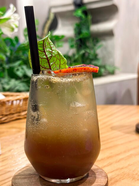 A glass of a cocktail with a black straw and a red tomato on the top.