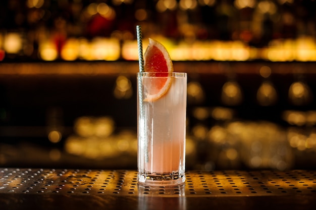 Glass of a cocktail with grapefruit on the wooden steel bar counter