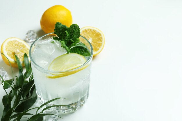 Glass of cocktail with lemon on white surface