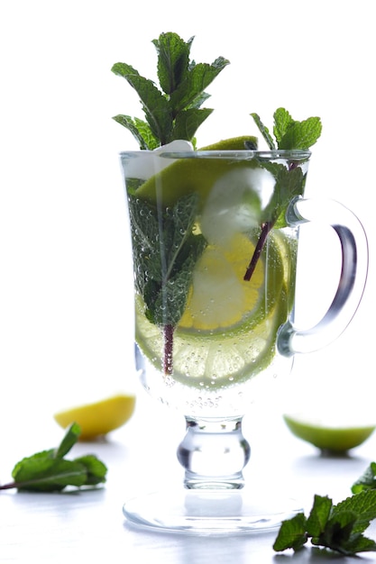 Glass of cocktail with mint and citrus fruits on a light background Fresh healthy cold lemon beverage Water with lemon Closeup