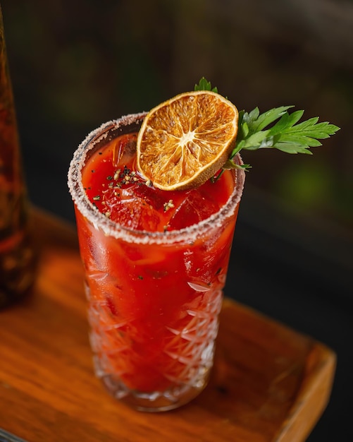 A glass of cocktail with a slice of tomato on top