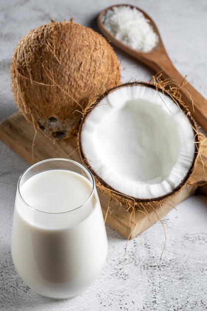 Glass of coconut milk with pieces of coconut on the table