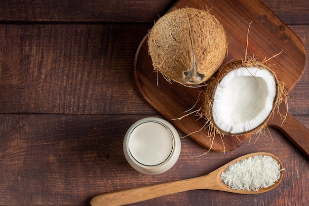 Glass of coconut milk with pieces of coconut on the table