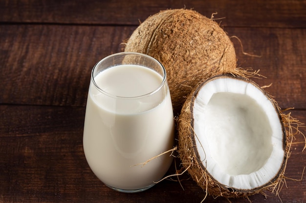 Glass of coconut milk with pieces of coconut on the table