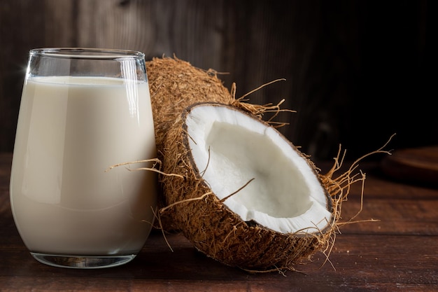 Glass of coconut milk with pieces of coconut on the table