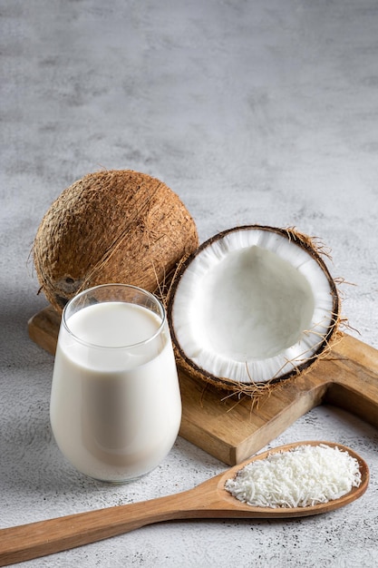 Glass of coconut milk with pieces of coconut on the table