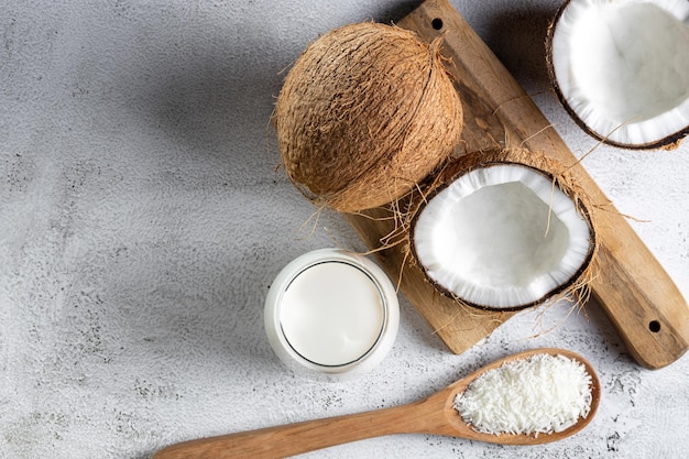 Glass of coconut milk with pieces of coconut on the table