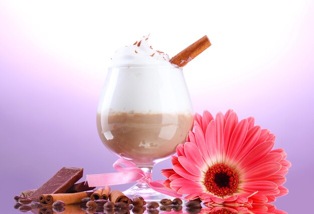 Glass of coffee cocktail and gerbera flower on purple background