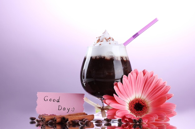 Glass of coffee cocktail and gerbera flower on purple background