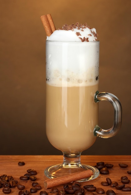 Glass of coffee cocktail with coffee beans on brown background