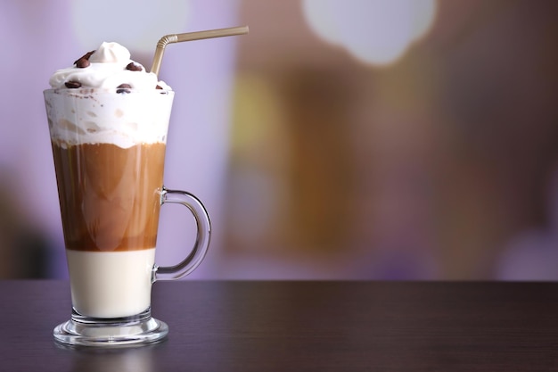 Glass of coffee on color wooden table on dark background