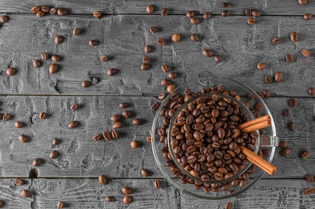 Glass coffee Cup with coffee beans on a black table with scattered coffee beans. The view from the top. Flat lay. Grains for the preparation of the popular drink.