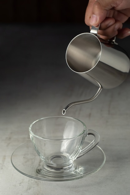 Foto bicchiere di caffè e brocca in acciaio inossidabile sul tavolo di cemento