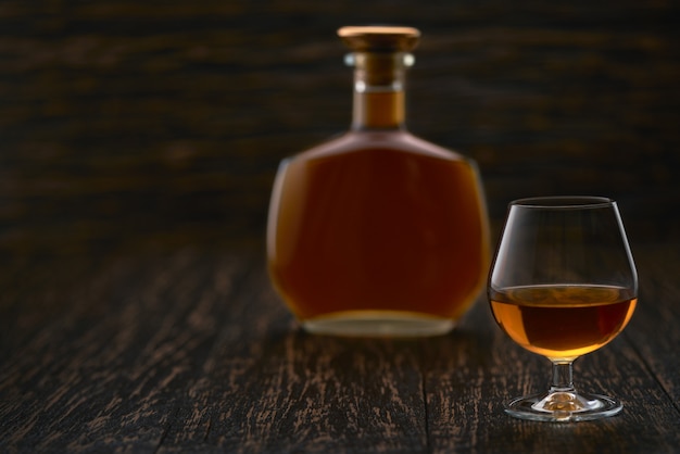 Glass of cognac on a black wooden table.