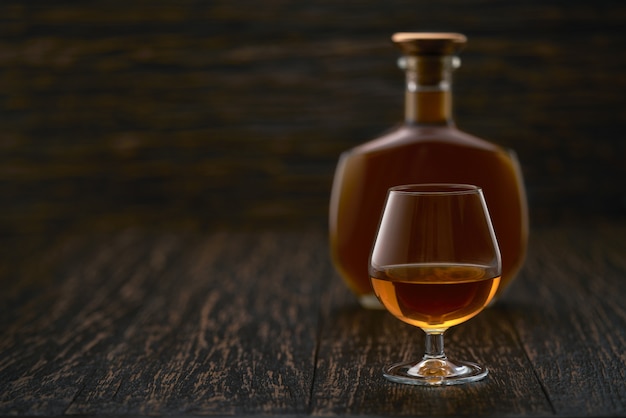 Glass of cognac on a black wooden table.