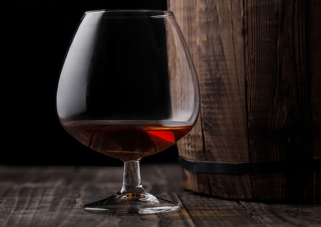 Glass of cognac brandy drink next to wooden barrel