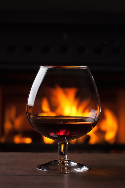 A glass of cognac in front of fireplace