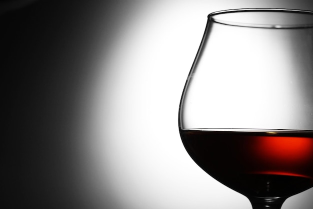 Glass of cognac on grey background