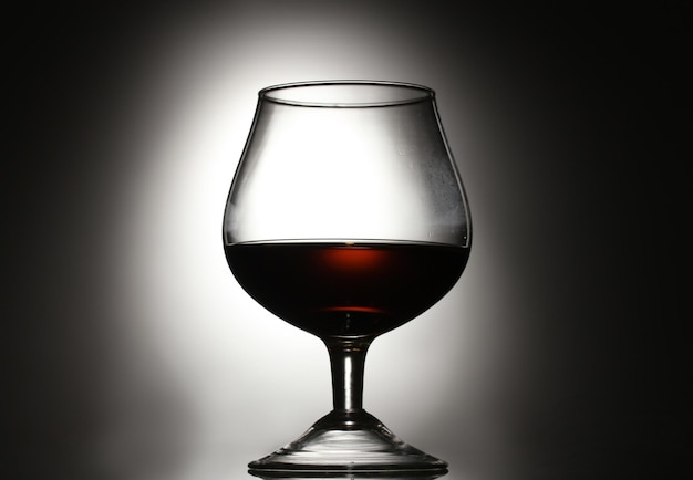 Glass of cognac on grey background