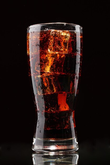 Glass of cola with ice on black background