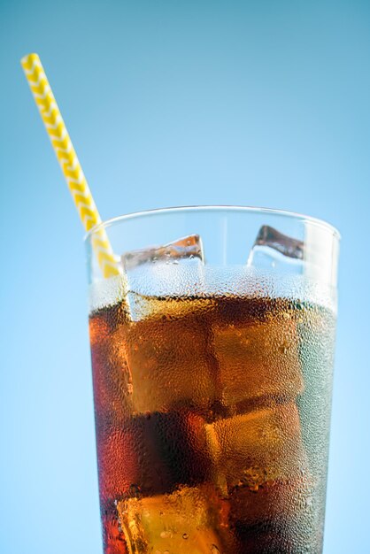 Photo a glass of cola with ice on blue and pink background