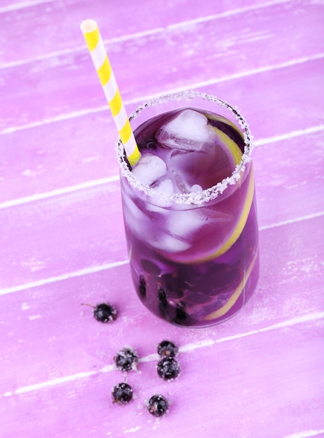 Glass of cold berry cocktail on wooden background