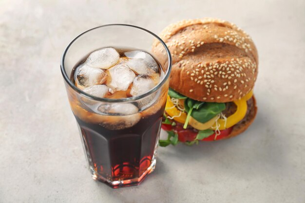 Foto un bicchiere di cola fredda con un buon hamburger sul tavolo .