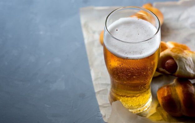 Un bicchiere di birra chiara fredda e salsiccia su uno spazio di copia tavolo in cemento