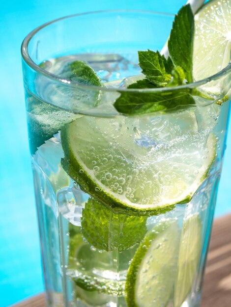 A glass of cold lime and mint drink near a swimming pool