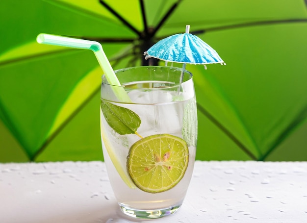 Photo glass of cold lime water with umbrella