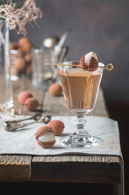 Glass of cold lychee cocktail on the old wooden table, rustic style