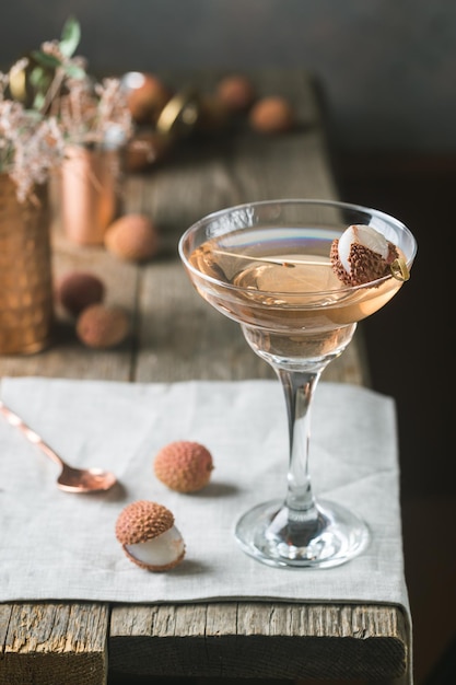 Glass of cold lychee cocktail on the old wooden table, rustic style