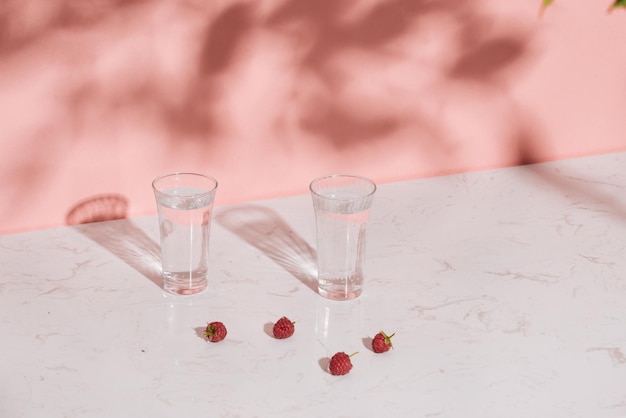 Glass of cold raspberry cider with fresh berries on light background