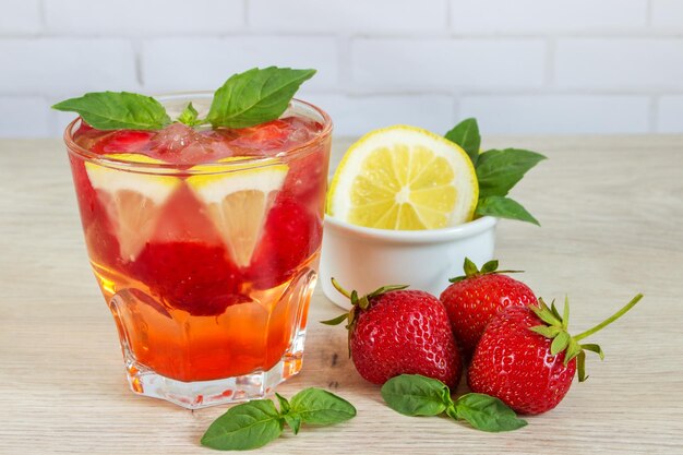 Photo glass of cold tea with mintstrawberrylemon on table