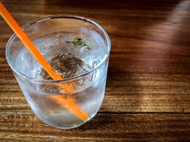 Glass of cold water and ice with orange tube for warm day 