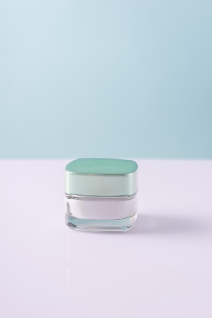 Glass container of cosmetic white cream on a whiteblue background minimalistic
