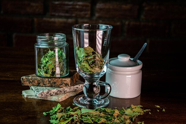 Glass containers with dried leaves on stones and wooden table